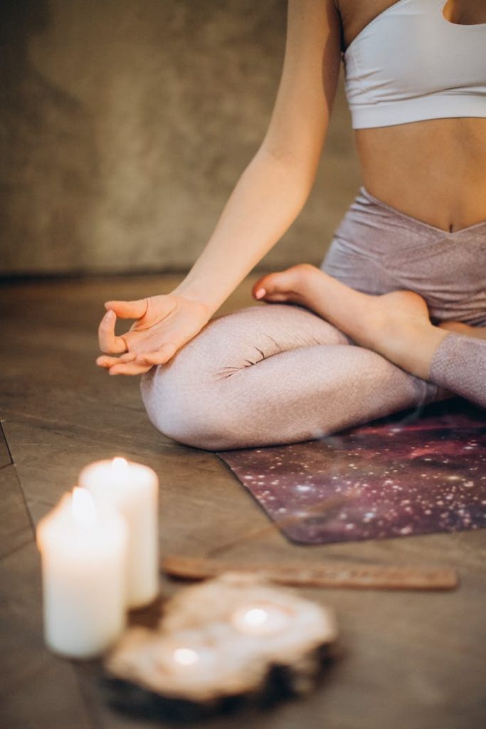 pexels-photo-3822621 A woman practicing yoga indoors in lotus pose with candles creating a calming atmosphere.
